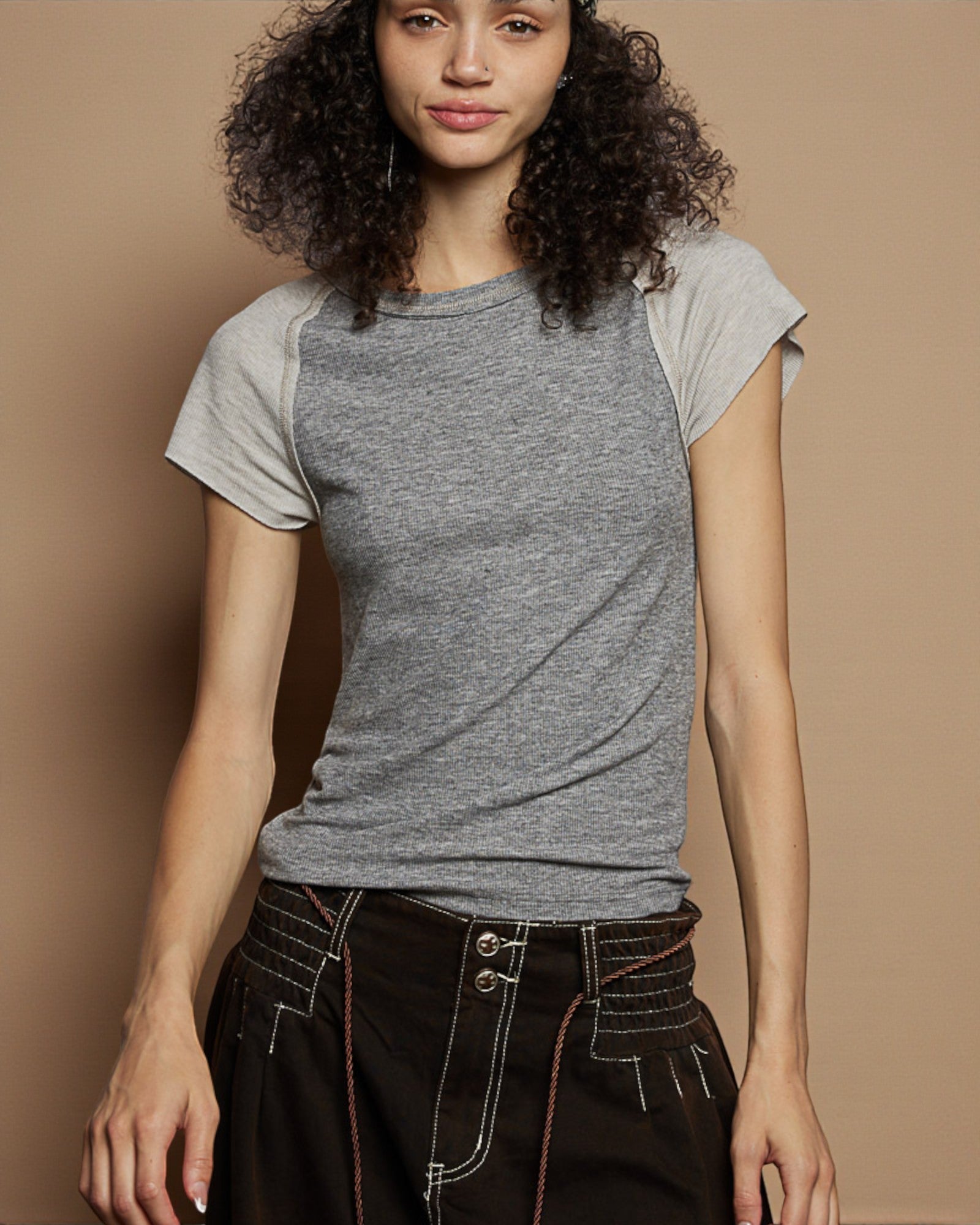 Woman wearing a gray t-shirt against a beige background