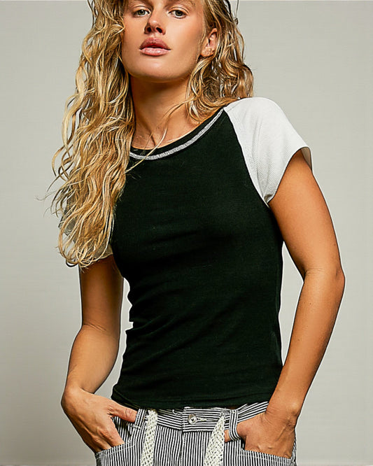 Woman wearing a black and white baseball shirt against a plain background