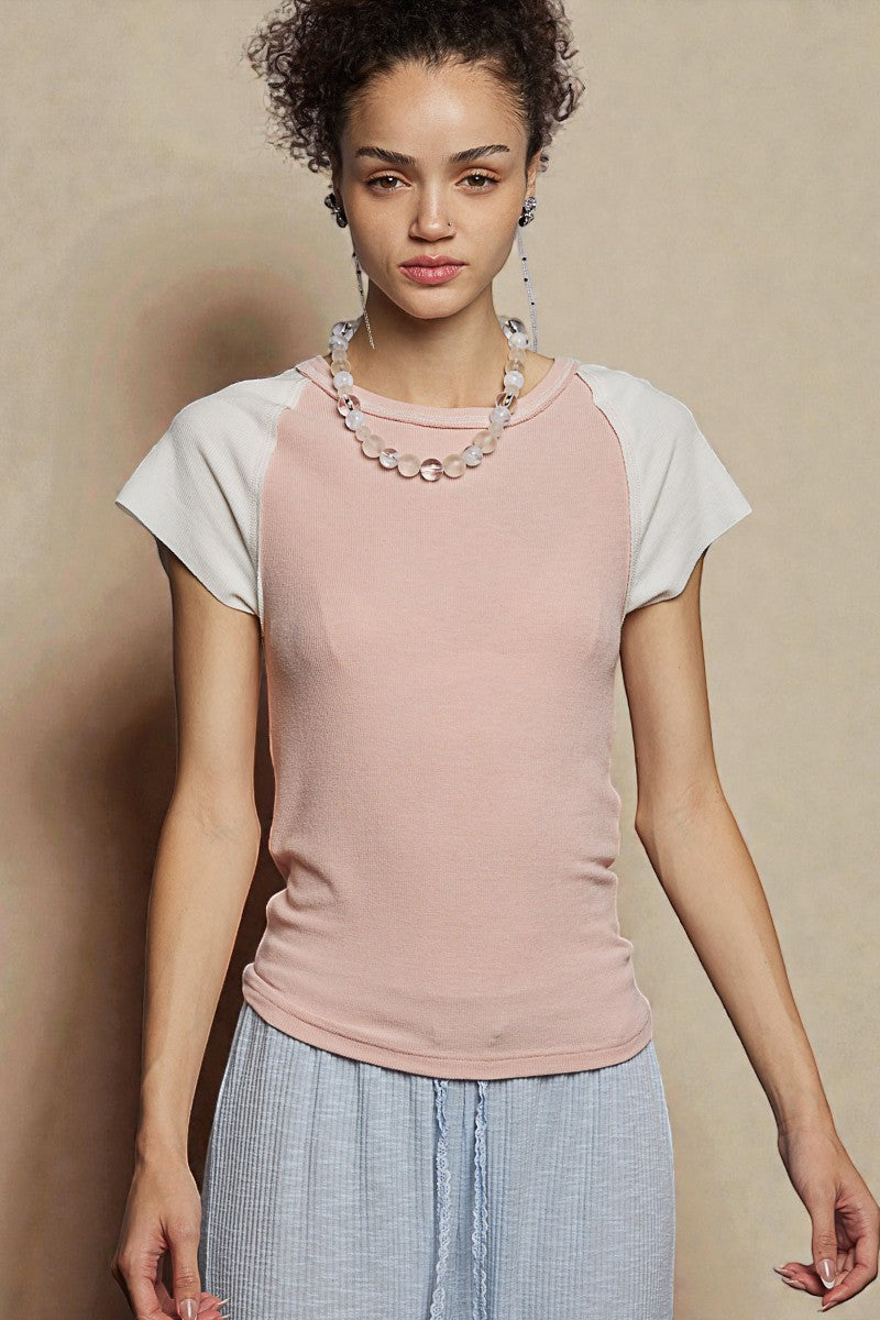 Woman wearing a pink and white top with a beige background