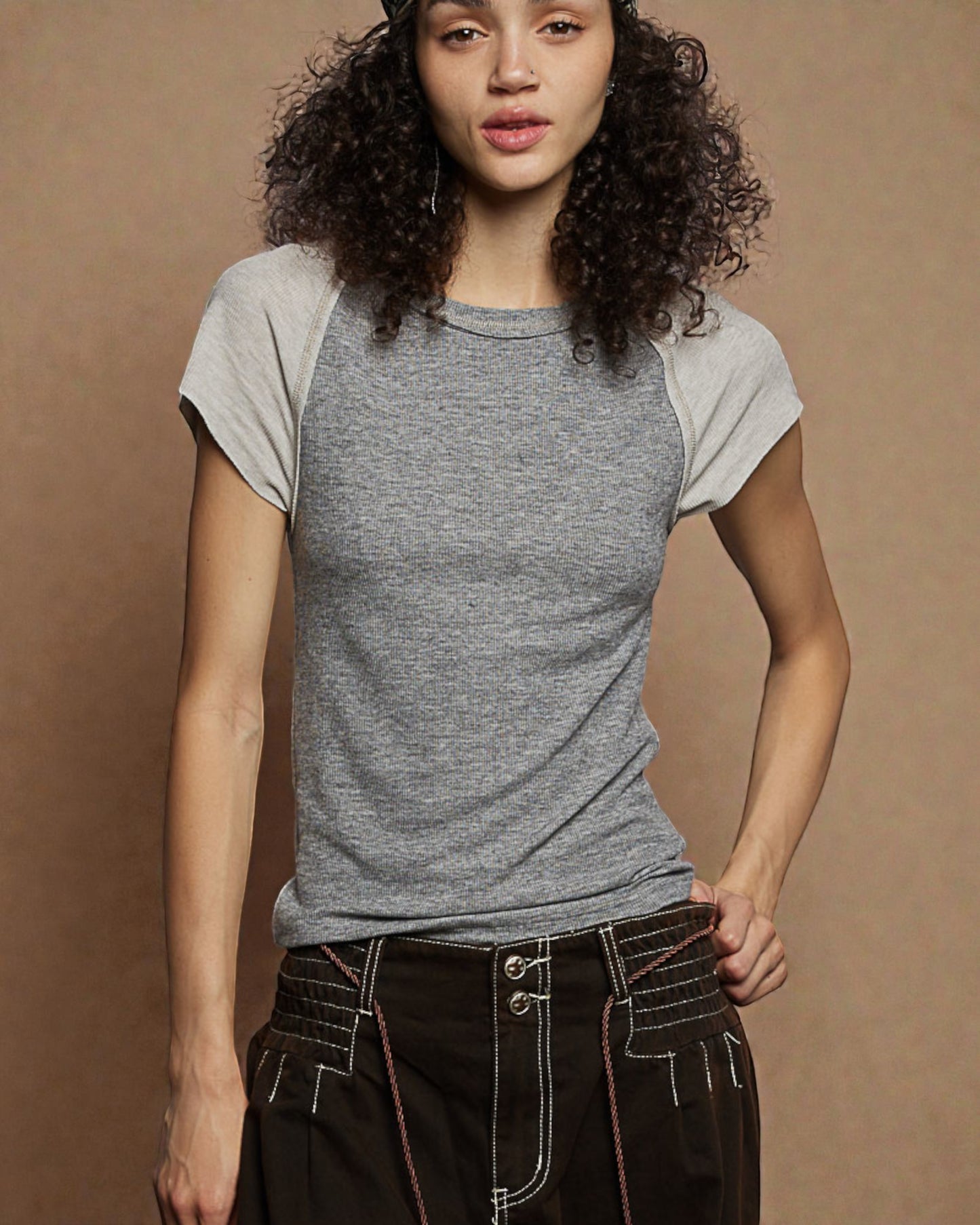 Woman wearing a gray and white t-shirt against a brown background