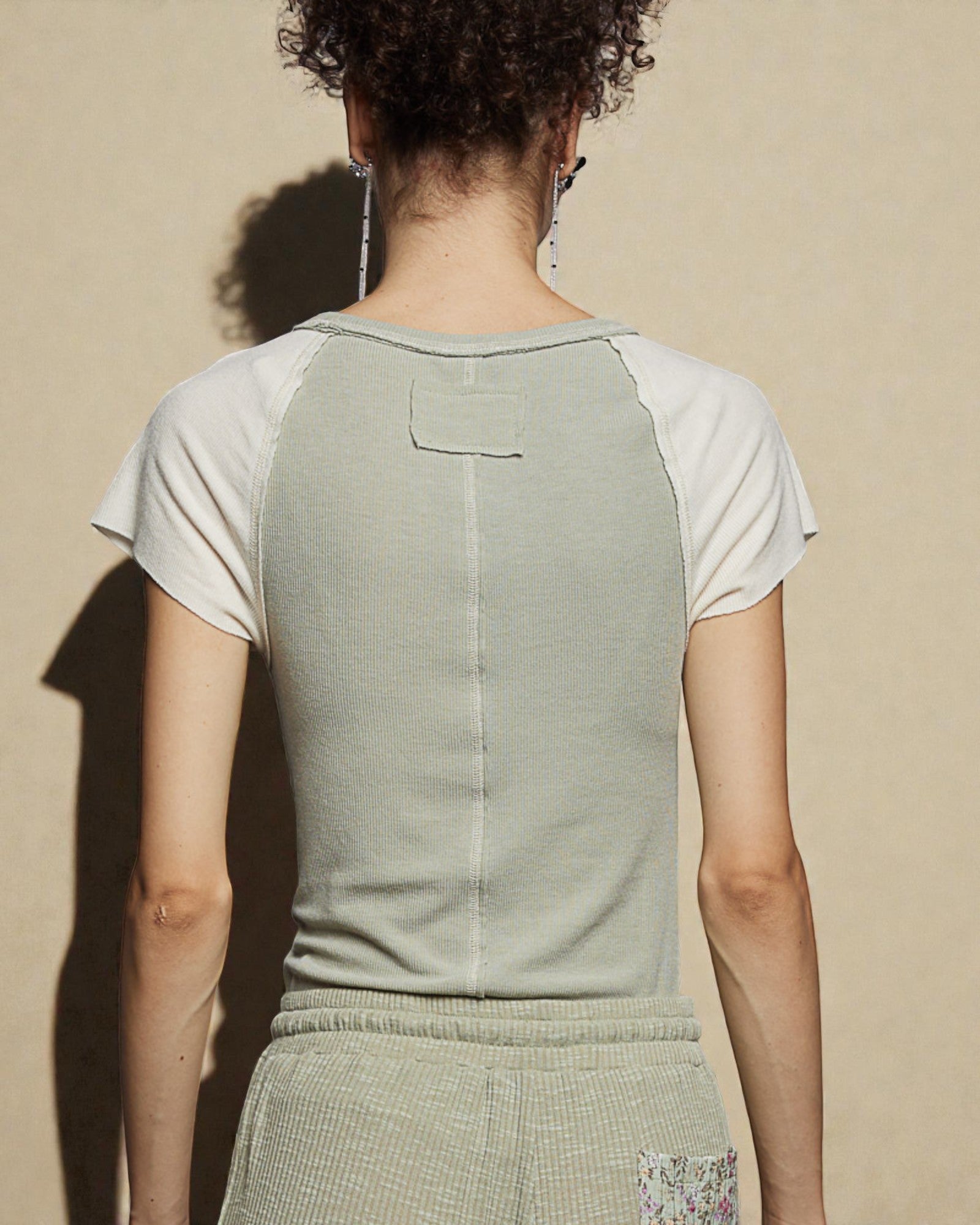 Person wearing a green and white shirt against a beige background