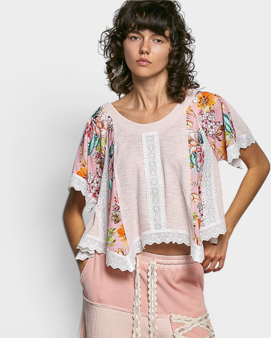 Woman wearing a floral kimono-style jacket over a pink top and skirt on a white background