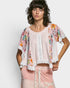 Woman wearing a floral kimono-style jacket over a pink top and skirt on a white background