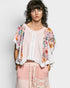 Woman wearing a floral kimono over a pink top and pants on a white background