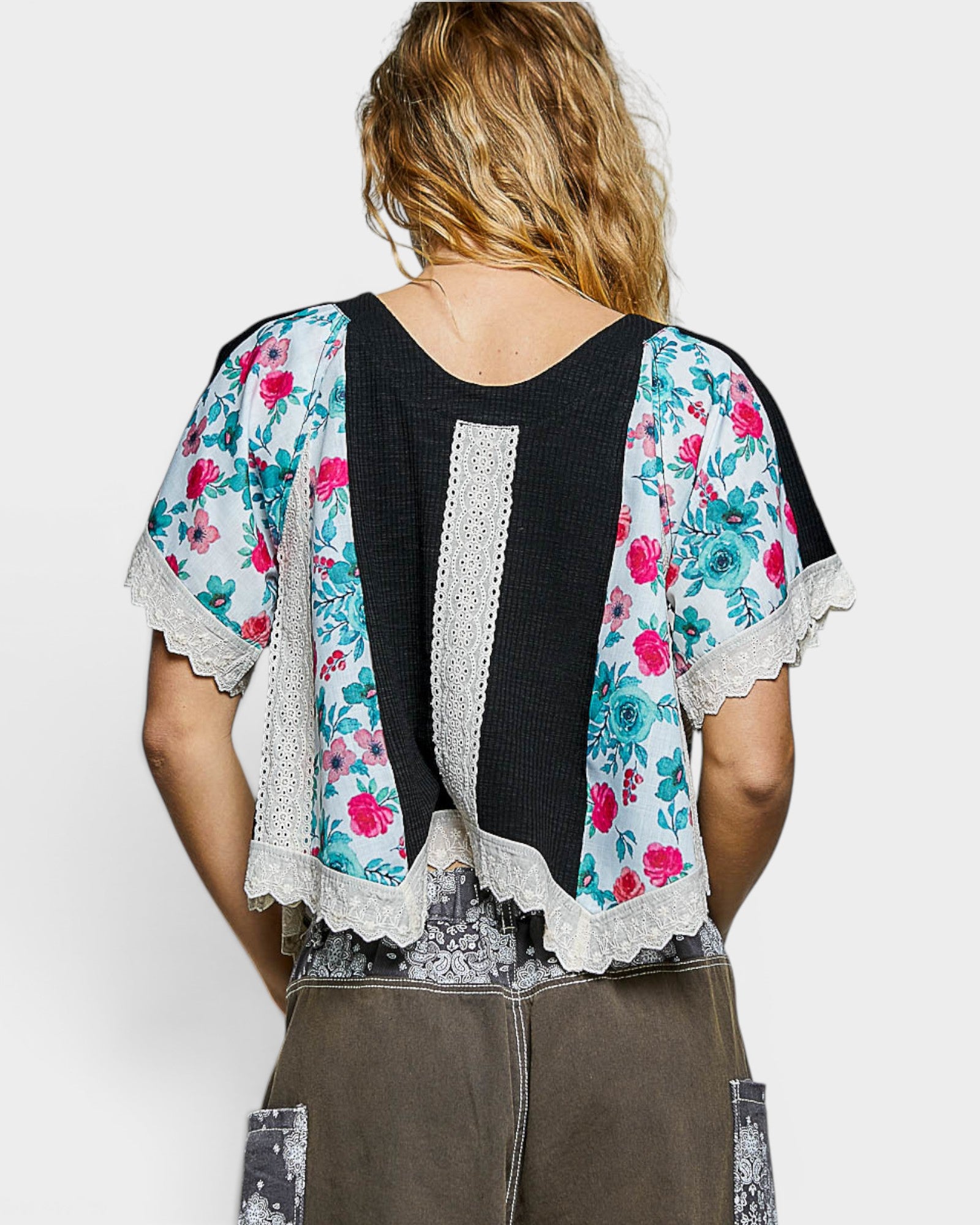 Woman wearing a floral kimono-style top over a black lace top on a white background