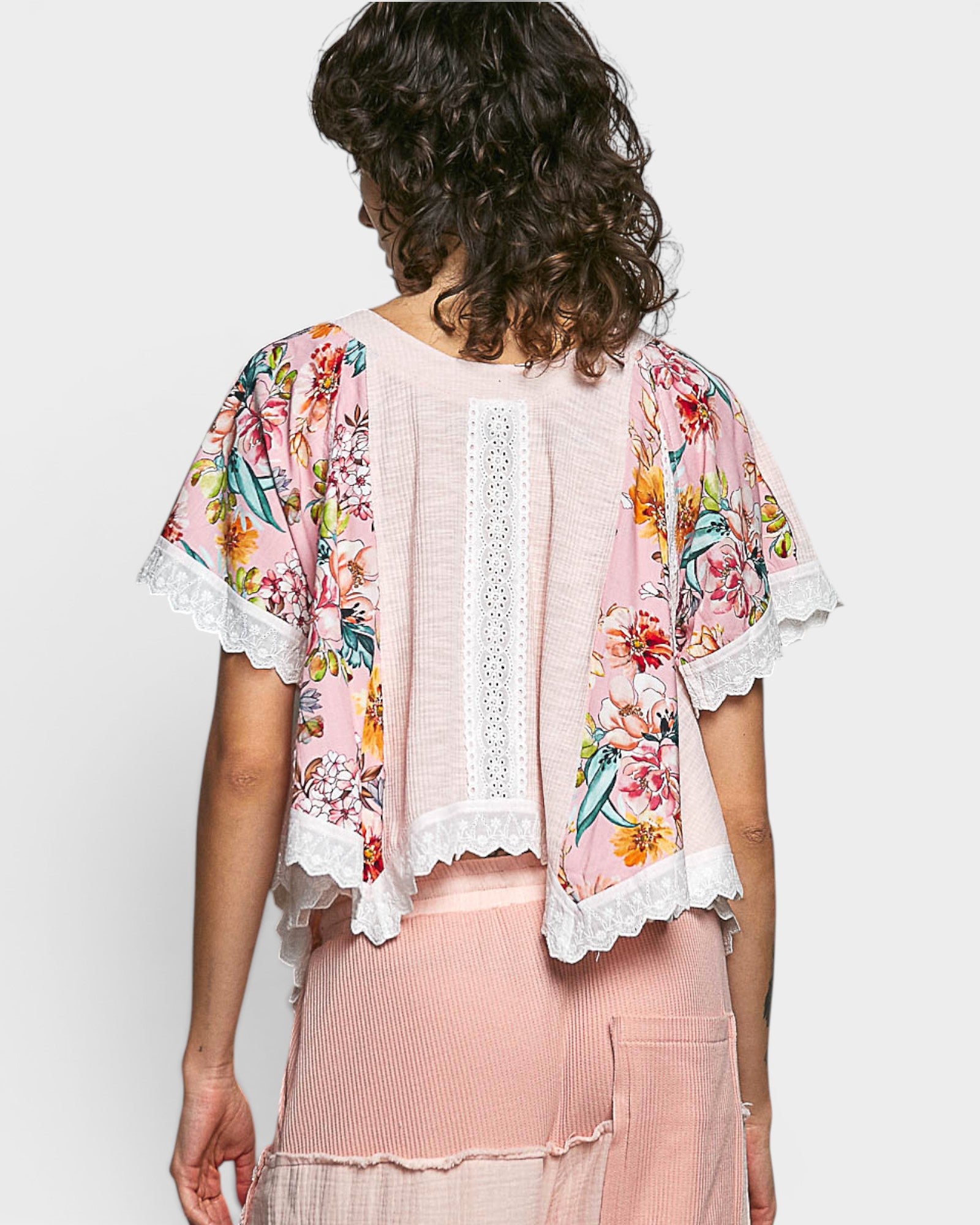 Woman wearing a floral kimono-style jacket over a pink outfit on a white background