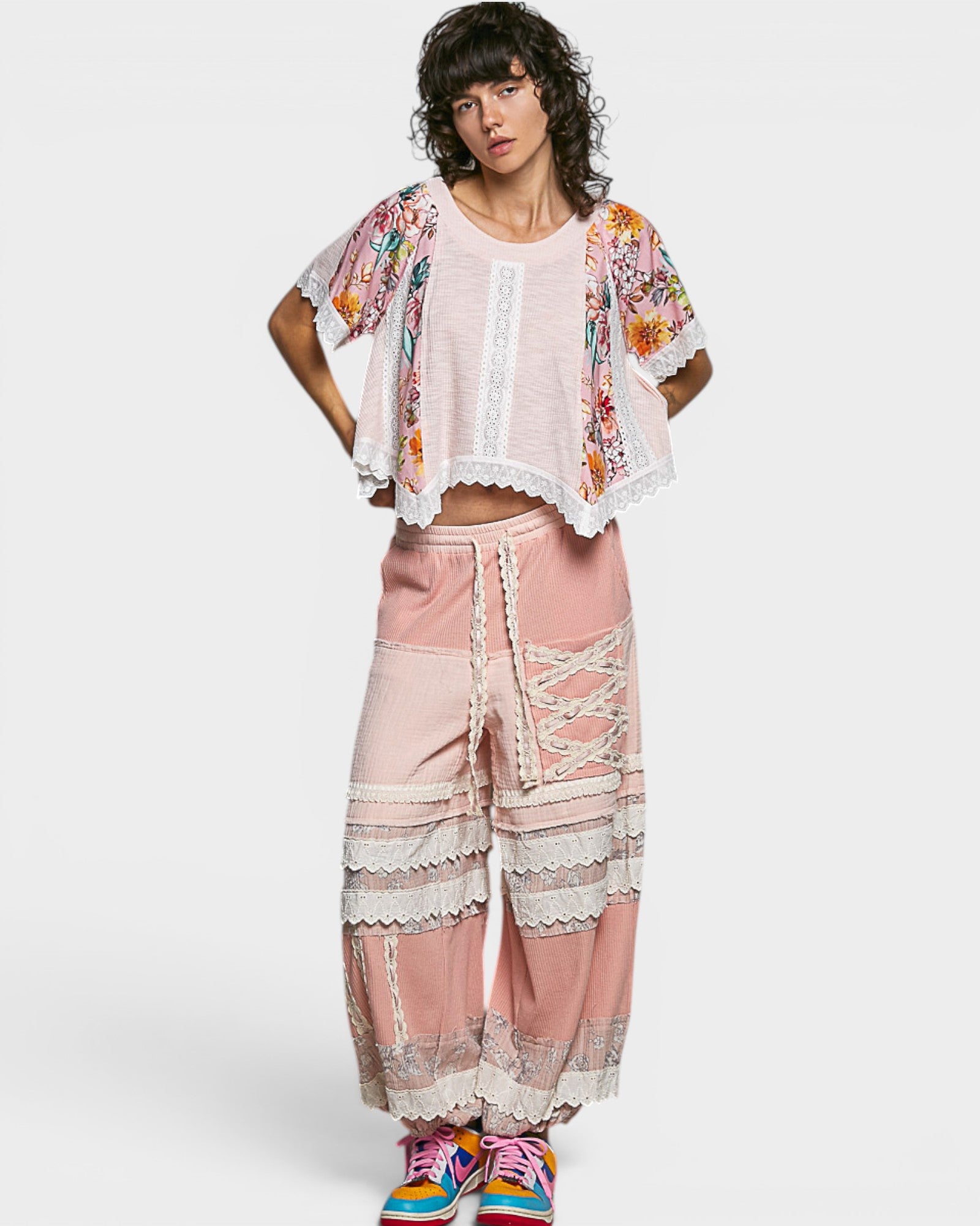 Woman wearing a floral kimono and pink lace pants on a white background