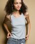 Woman wearing a light gray tank top and blue jeans against a beige background