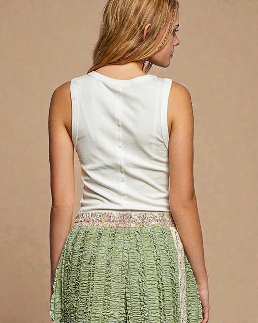 Woman wearing a white sleeveless top and green textured skirt on a beige background