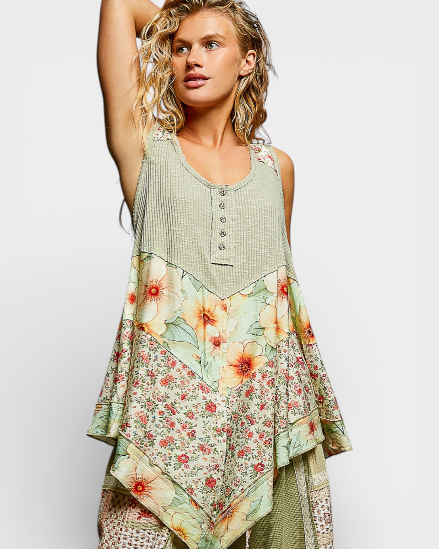 Woman wearing a sleeveless top with floral patterns on a plain background