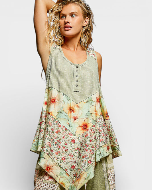 Woman wearing a sleeveless top with floral patterns on a plain background