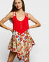 Woman wearing a red top with floral patterns on a plain background