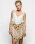 Woman wearing a white top with floral skirt on a plain background