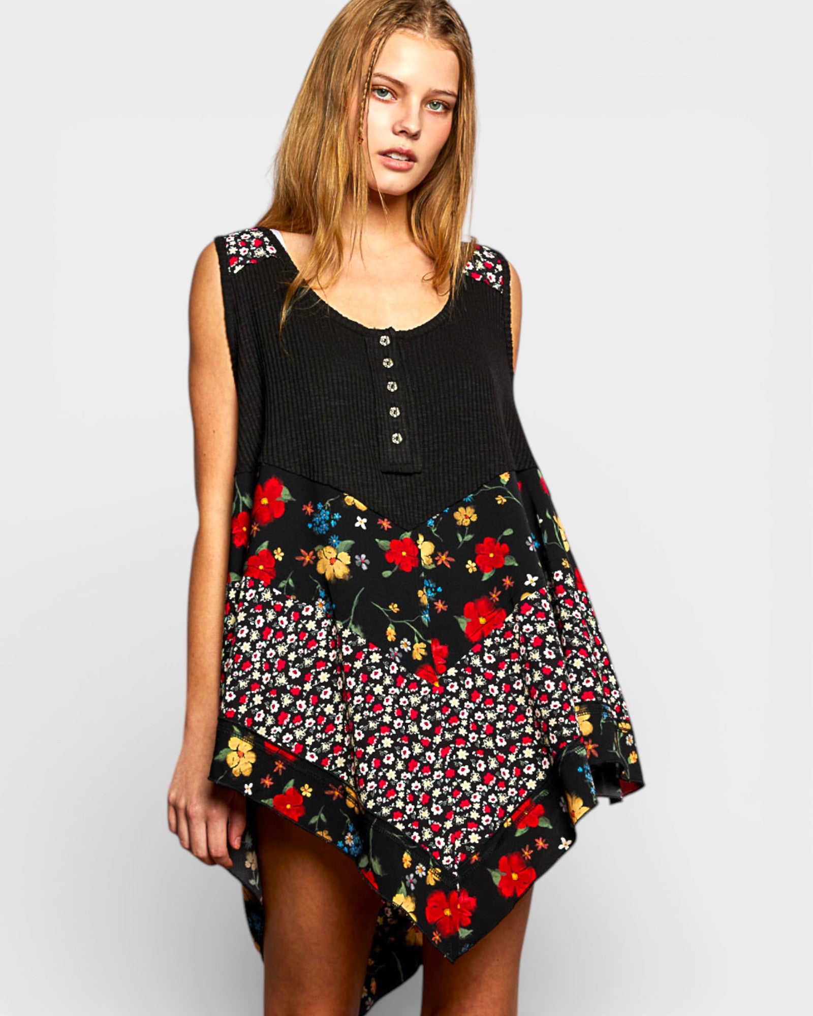 Woman wearing a black sleeveless top with colorful floral patterns on a plain background