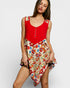 Woman wearing a red top and floral dress on a white background