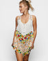 Woman wearing a white sleeveless top with floral skirt on a plain background
