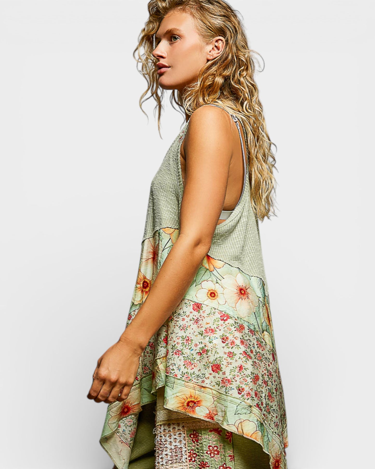 Woman wearing a sleeveless top with floral pattern on a plain background