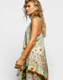 Woman wearing a sleeveless top with floral pattern on a plain background