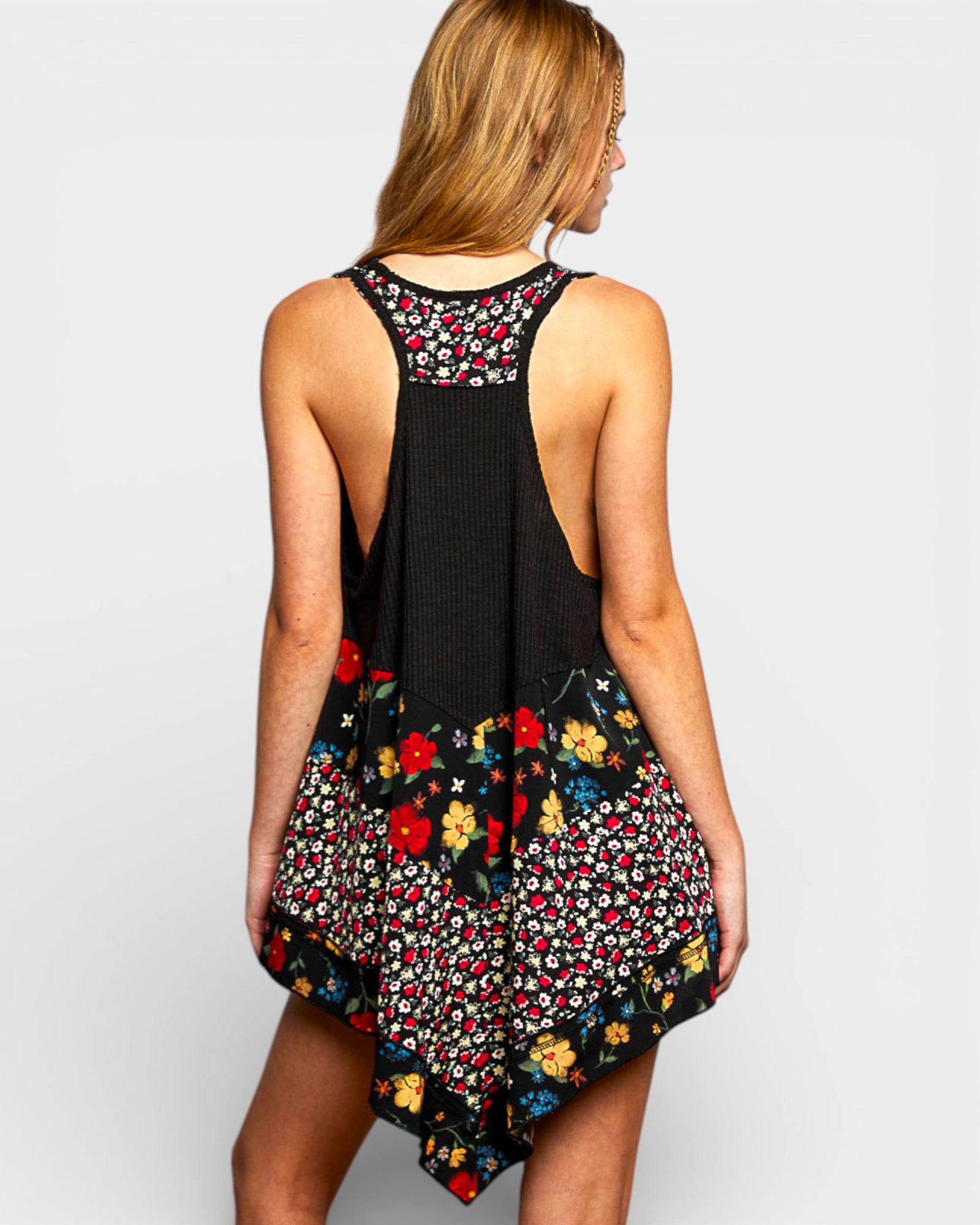 Woman wearing a black sleeveless top with colorful floral patterns on a plain background