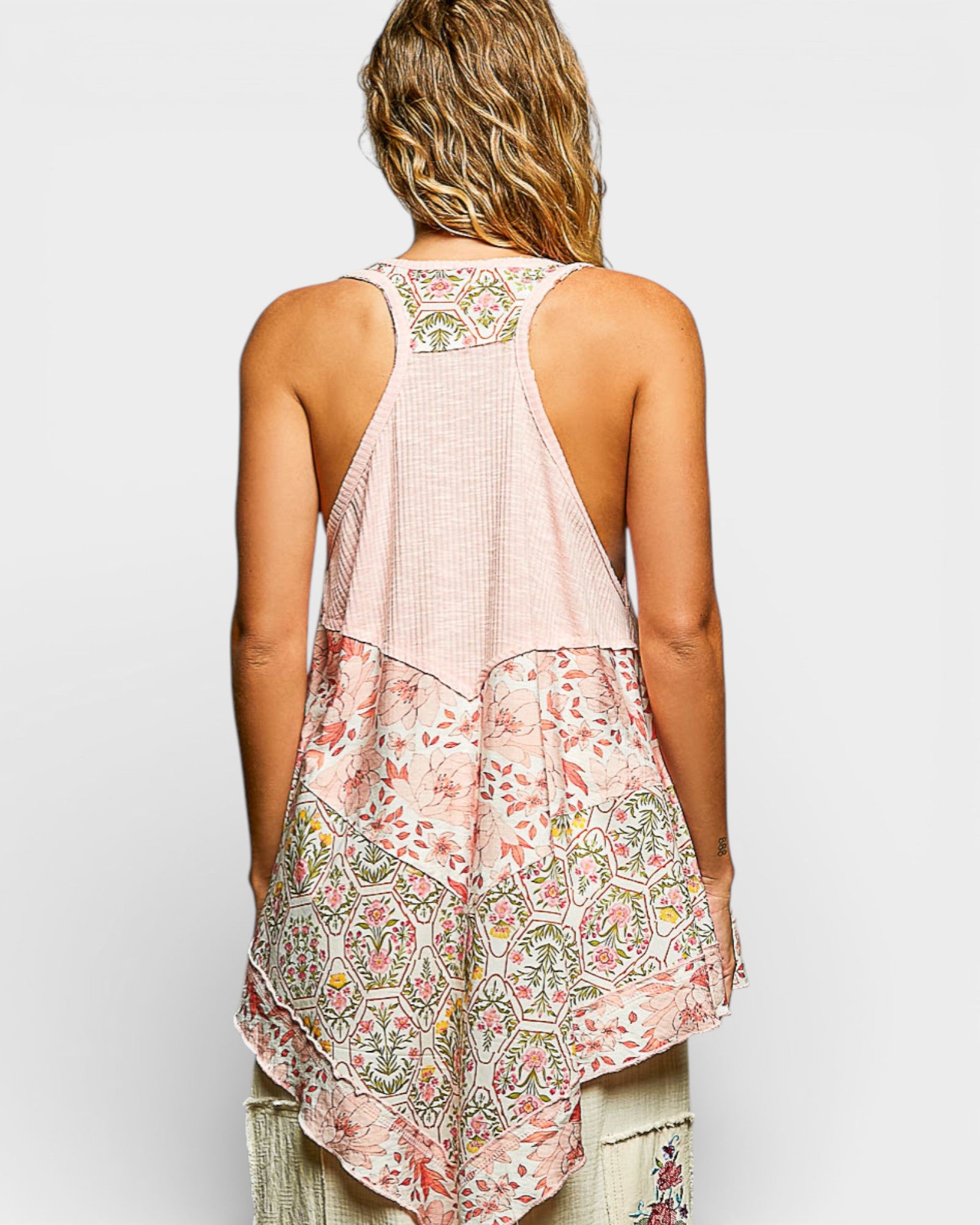 Woman wearing a sleeveless, patterned top with a plain background