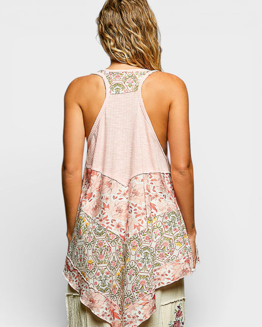 Woman wearing a sleeveless, patterned top with a plain background