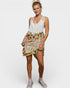 Woman wearing a white sleeveless top and colorful floral skirt on a white background