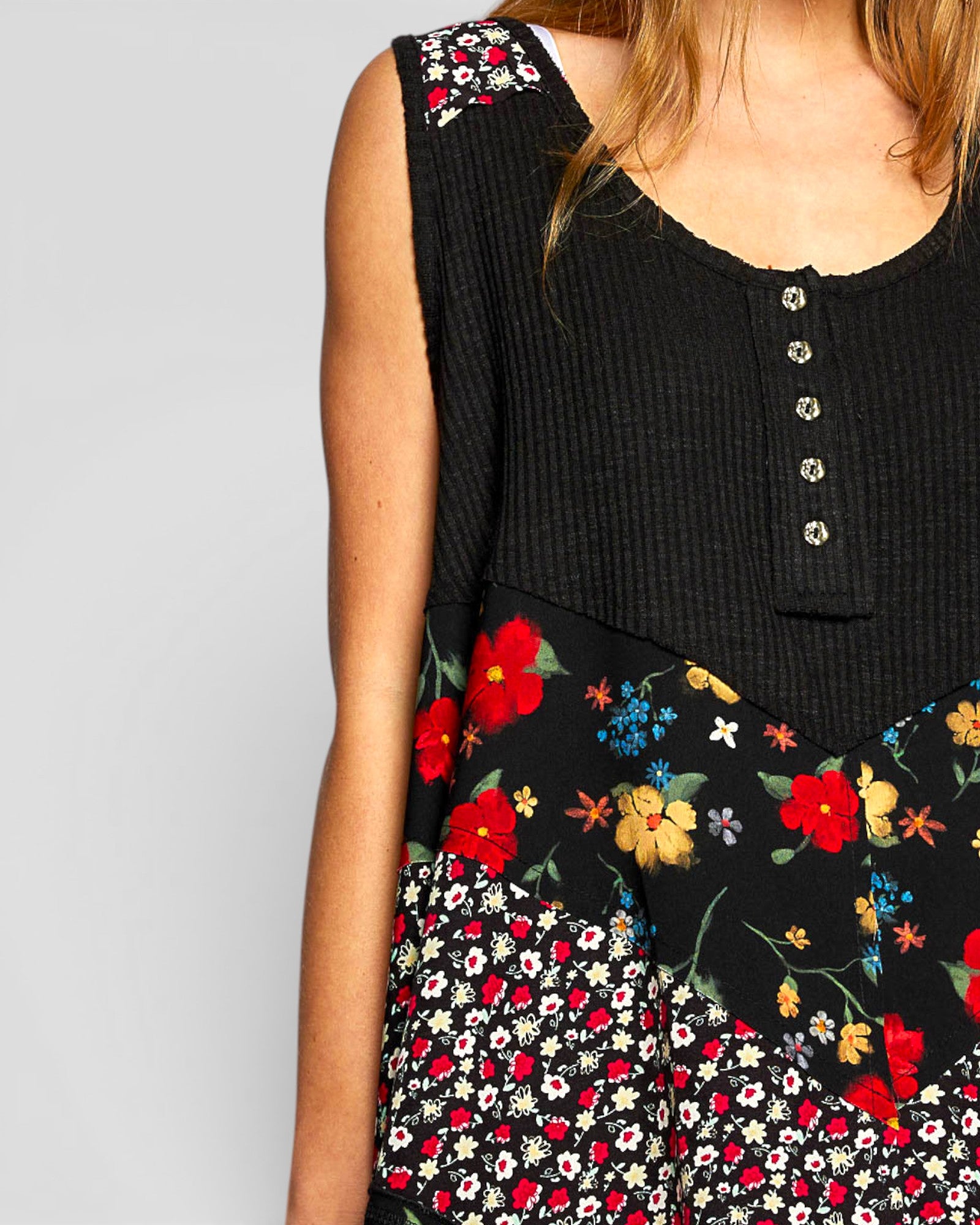 Black sleeveless top with floral patterns on a plain background
