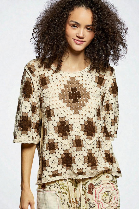 Woman wearing a brown and beige crochet top with floral pants on a white background