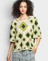 Woman wearing a green and white crochet top against a plain background