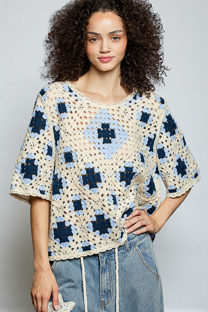 Woman wearing a crocheted top with a geometric pattern against a plain background