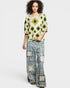 Woman wearing a patterned top and plaid pants with patches on a white background