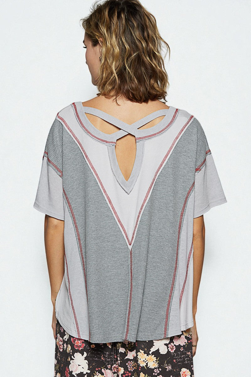 Woman wearing a gray blouse with a unique back design on a white background