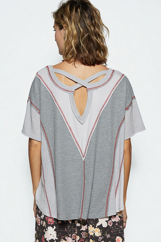 Woman wearing a gray blouse with a unique back design on a white background