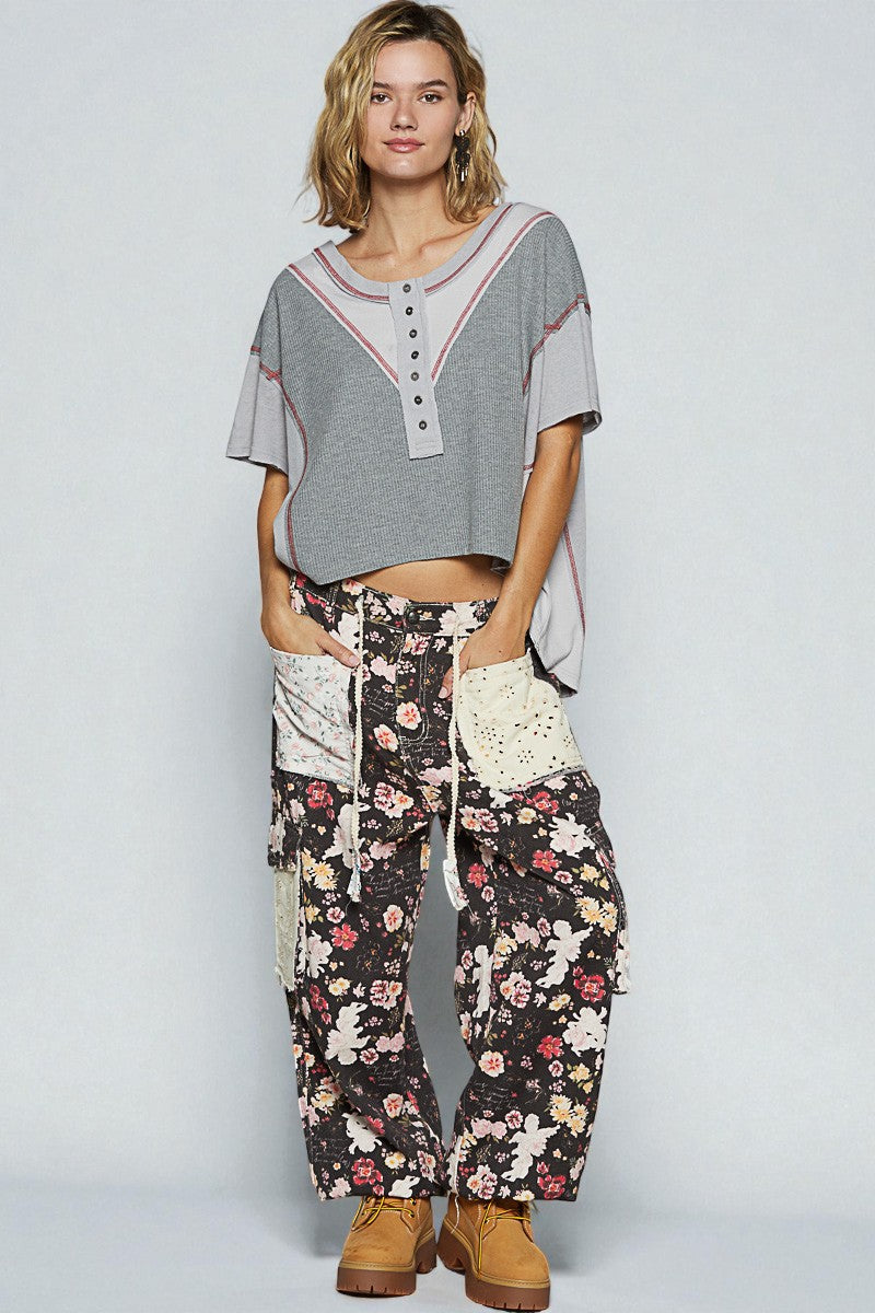 Woman wearing a gray top and floral pants on a plain background
