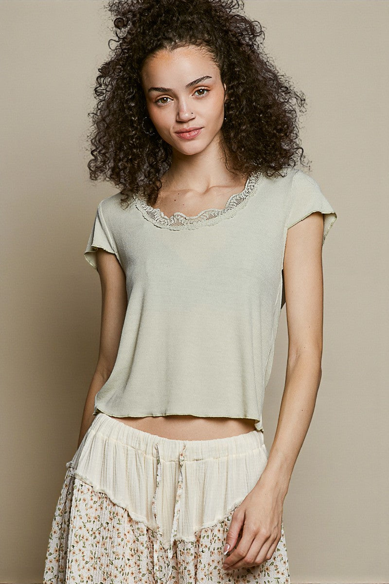 Woman wearing a light green top and white patterned pants against a beige background