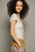 Woman wearing a beige top and patterned pants against a plain background