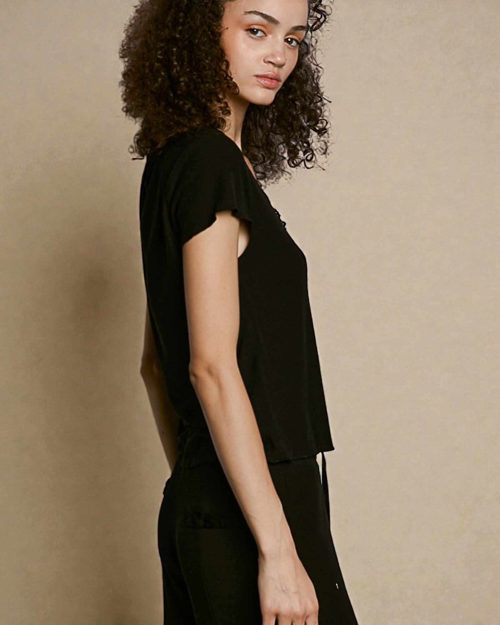 Woman wearing a black outfit against a beige background