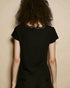 Person wearing a black top with lace details against a beige background
