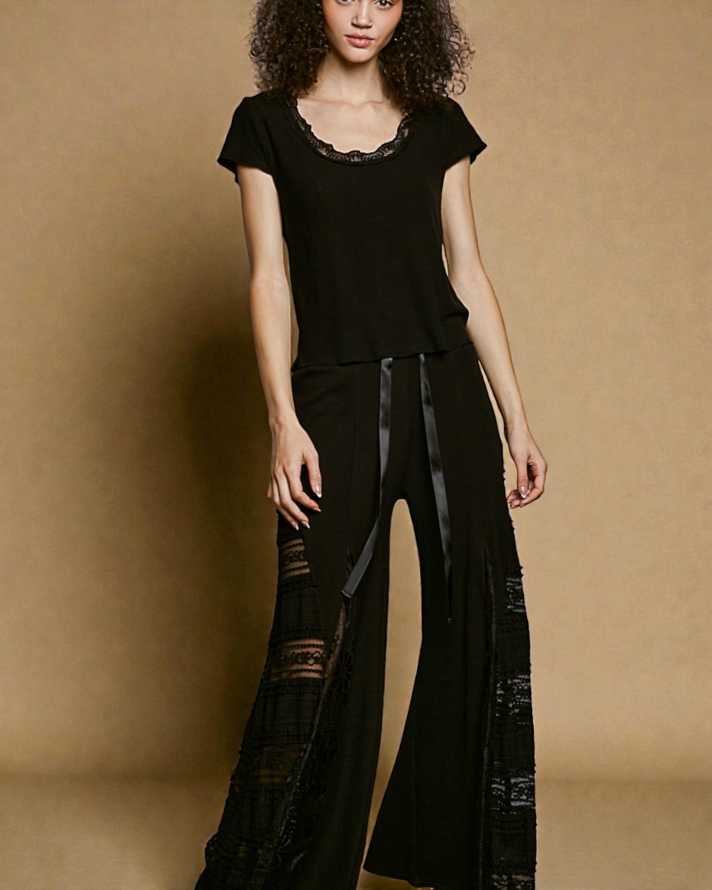 Woman wearing a black outfit with sheer panels against a brown background