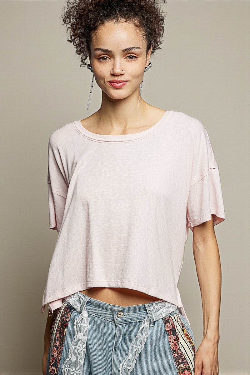 Woman wearing a light pink oversized t-shirt with patterned pants against a neutral background