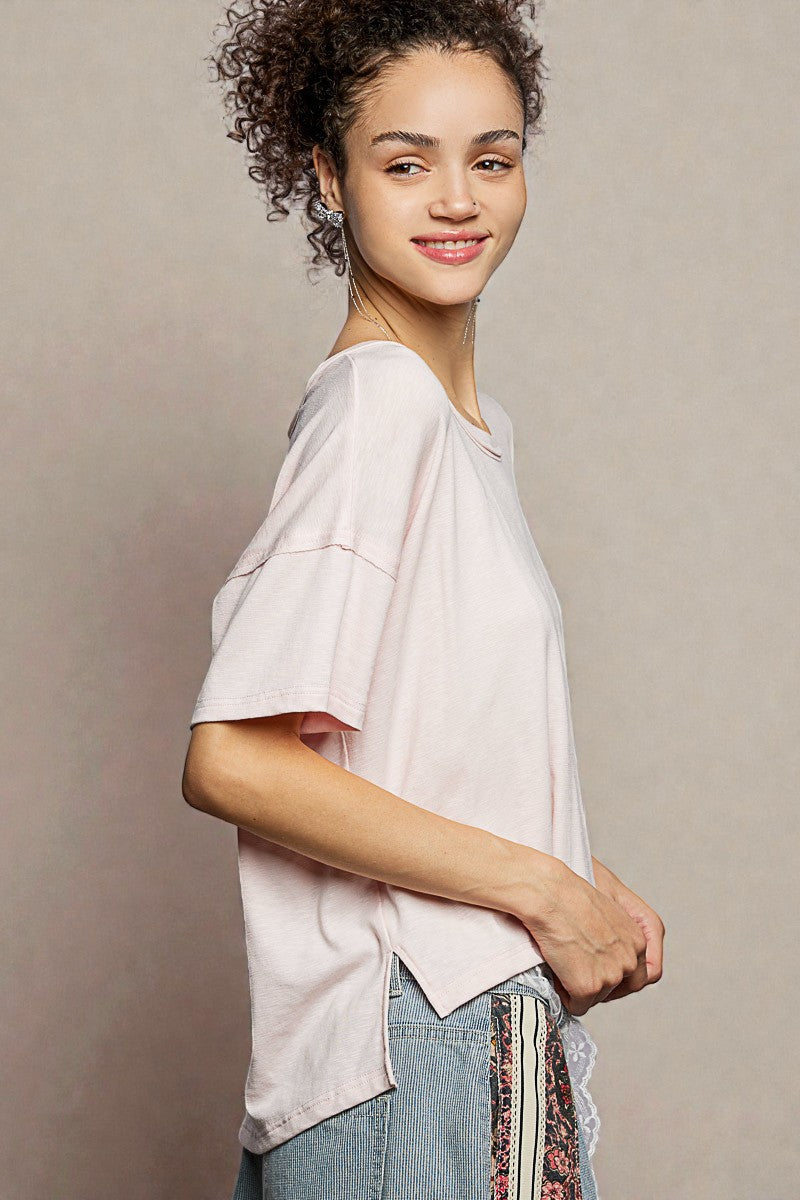 Woman wearing a light pink oversized shirt with a neutral background