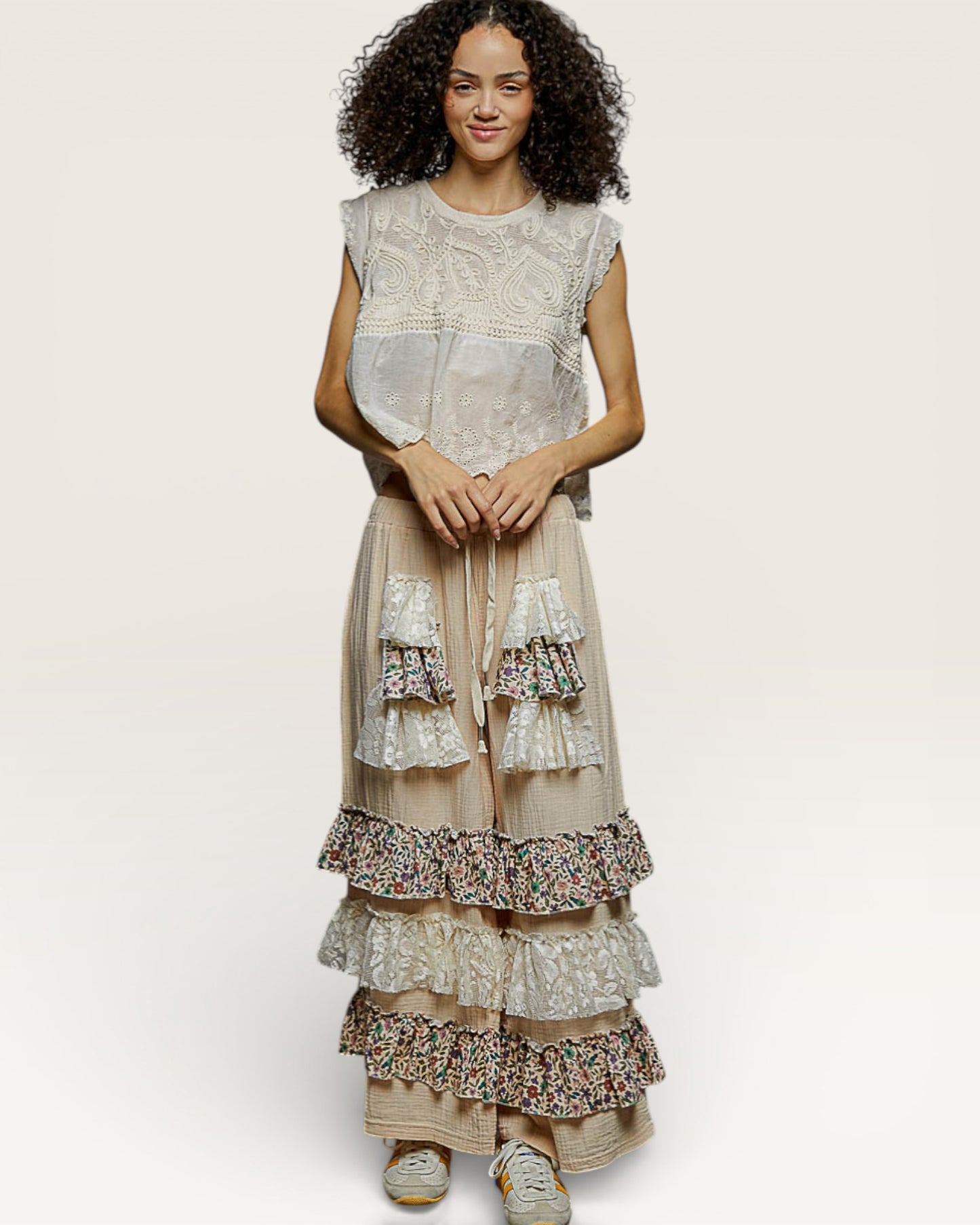 Woman wearing a layered dress with floral patterns on a plain background