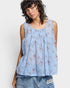 Woman wearing a light blue floral sleeveless top against a white background