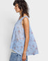 Woman wearing a light blue floral sleeveless top against a white background