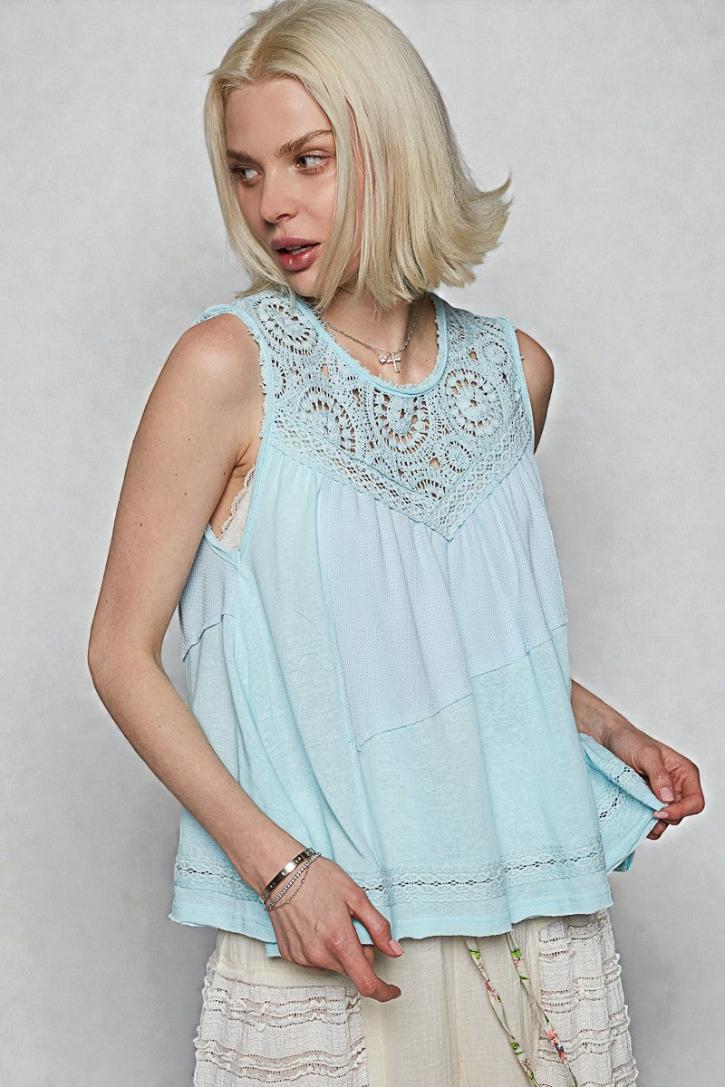 Woman wearing a light blue lace top against a plain background
