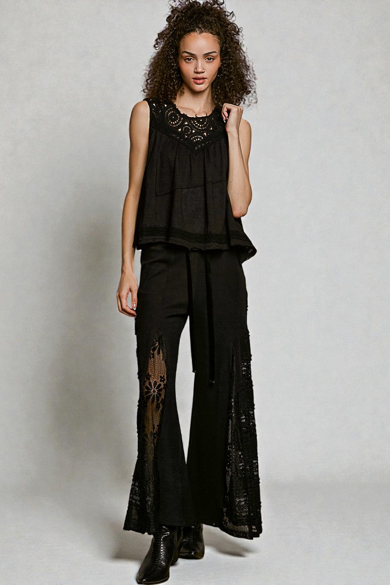 Woman wearing a black outfit with lace details on a plain background