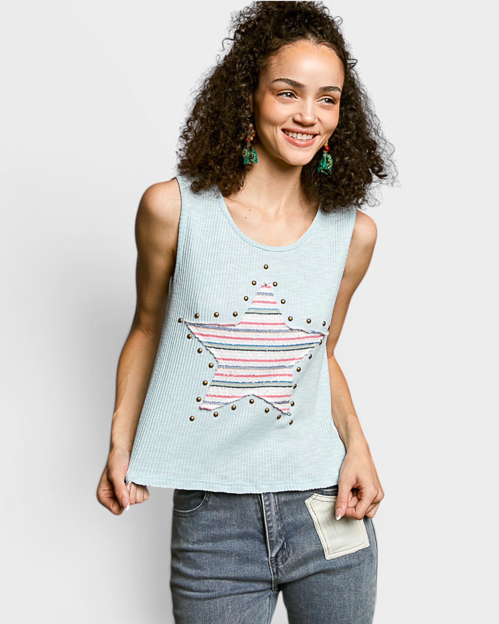 Woman wearing a light blue sleeveless top with a star design on a plain background