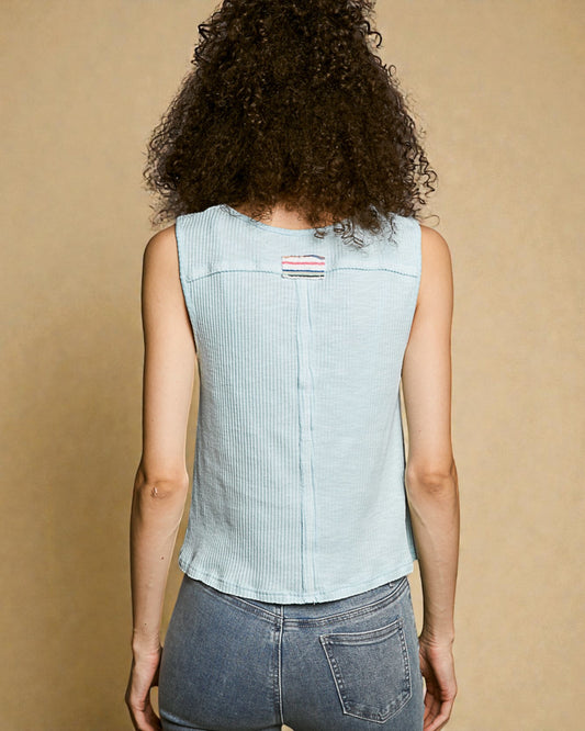 Person wearing a light blue sleeveless denim vest on a beige background
