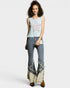 Woman wearing a light blue sleeveless top with a star design and high-waisted jeans with fringe details on a white background.