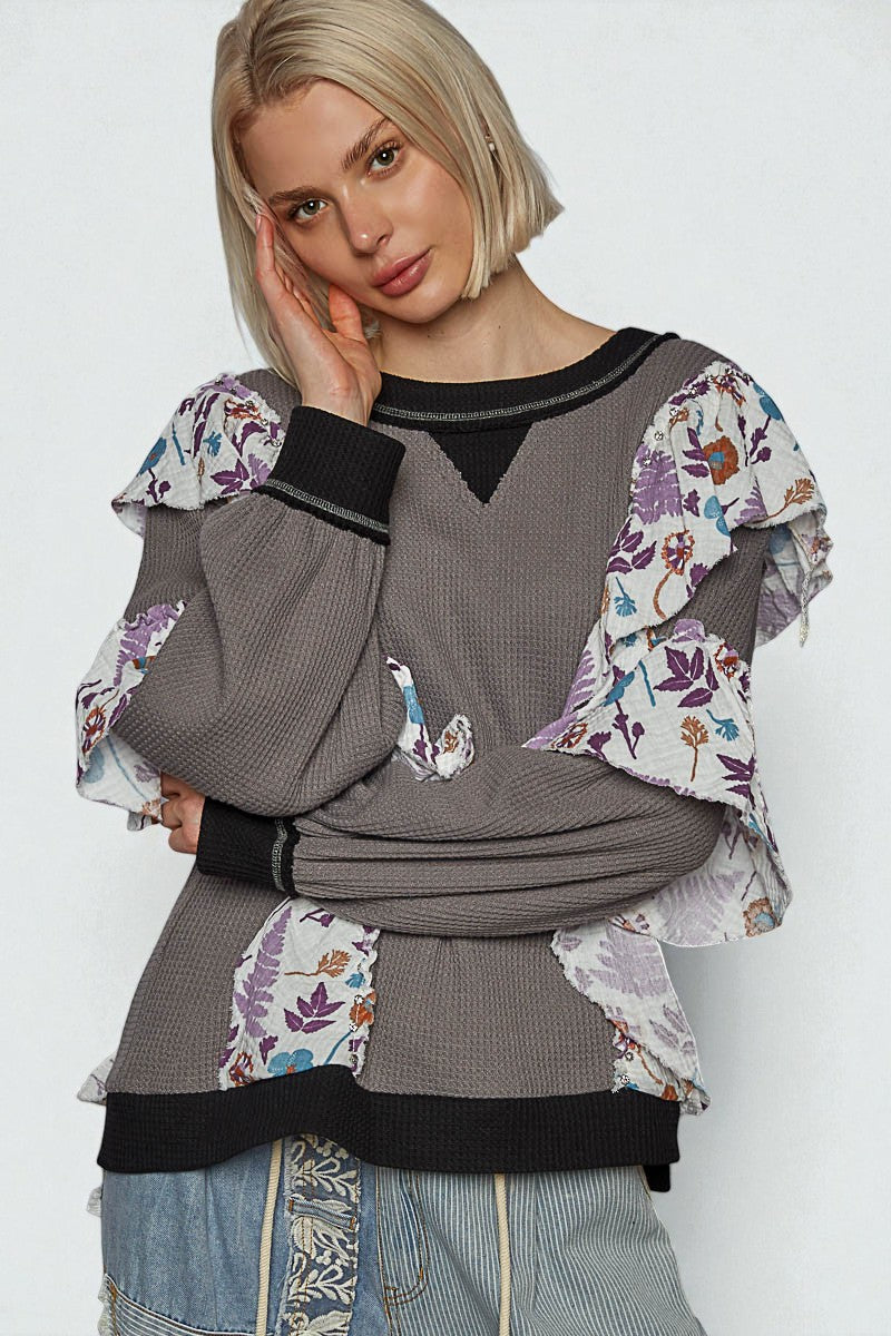 Woman wearing a gray sweater with floral patterns on a white background